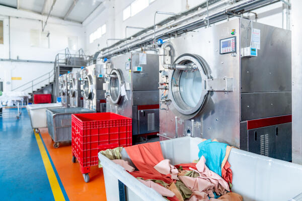 Textilreiniger arbeiten in der Wäschereihalle