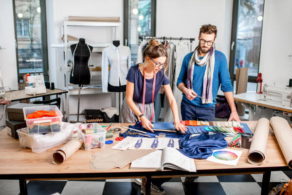 Modedesigner arbeiten am Tisch mit vielen Stoffen