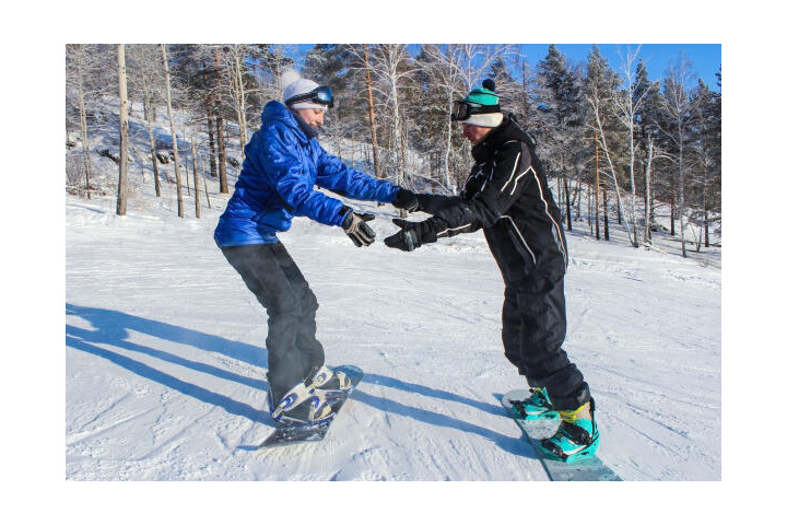 Snowboardlehrer unterstützt Schülerin beim Snowboarden