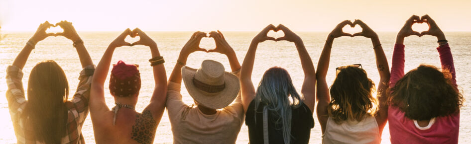 Jugendliche am Strand machen Herzsymbol