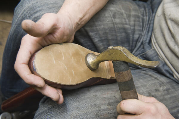 Maßschuhmacher arbeitet mit Hammer Maßschuhmacher arbeitet mit Hammer