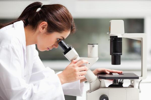 Edelmetallprüferin untersucht Zusammensetzungen unter dem Mikroskop Edelmetallprüferin untersucht Zusammensetzungen unter dem Mikroskop