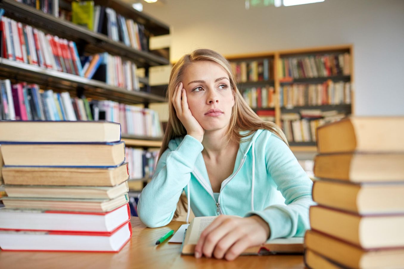 Klausurphase – Studierende ist umgeben von Buechern