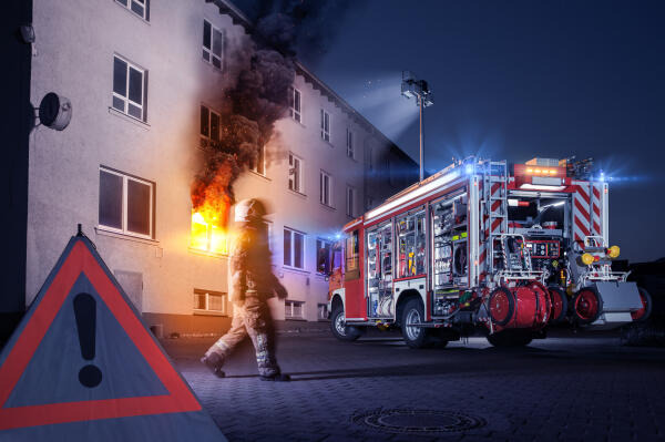 Löschfahrzeug vor brennendem Wohnhaus