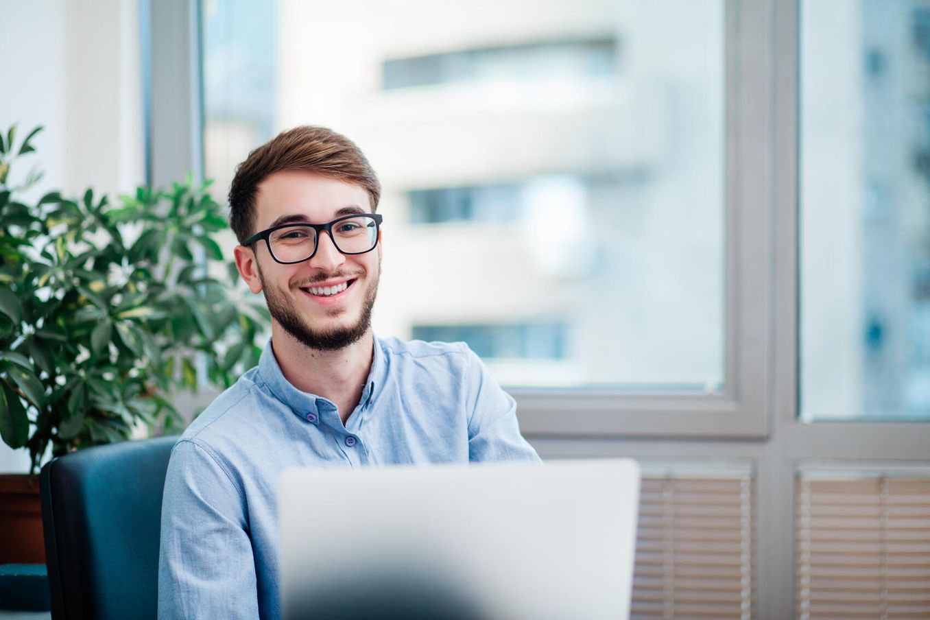Werkstudent lächelt am Laptop im Büro