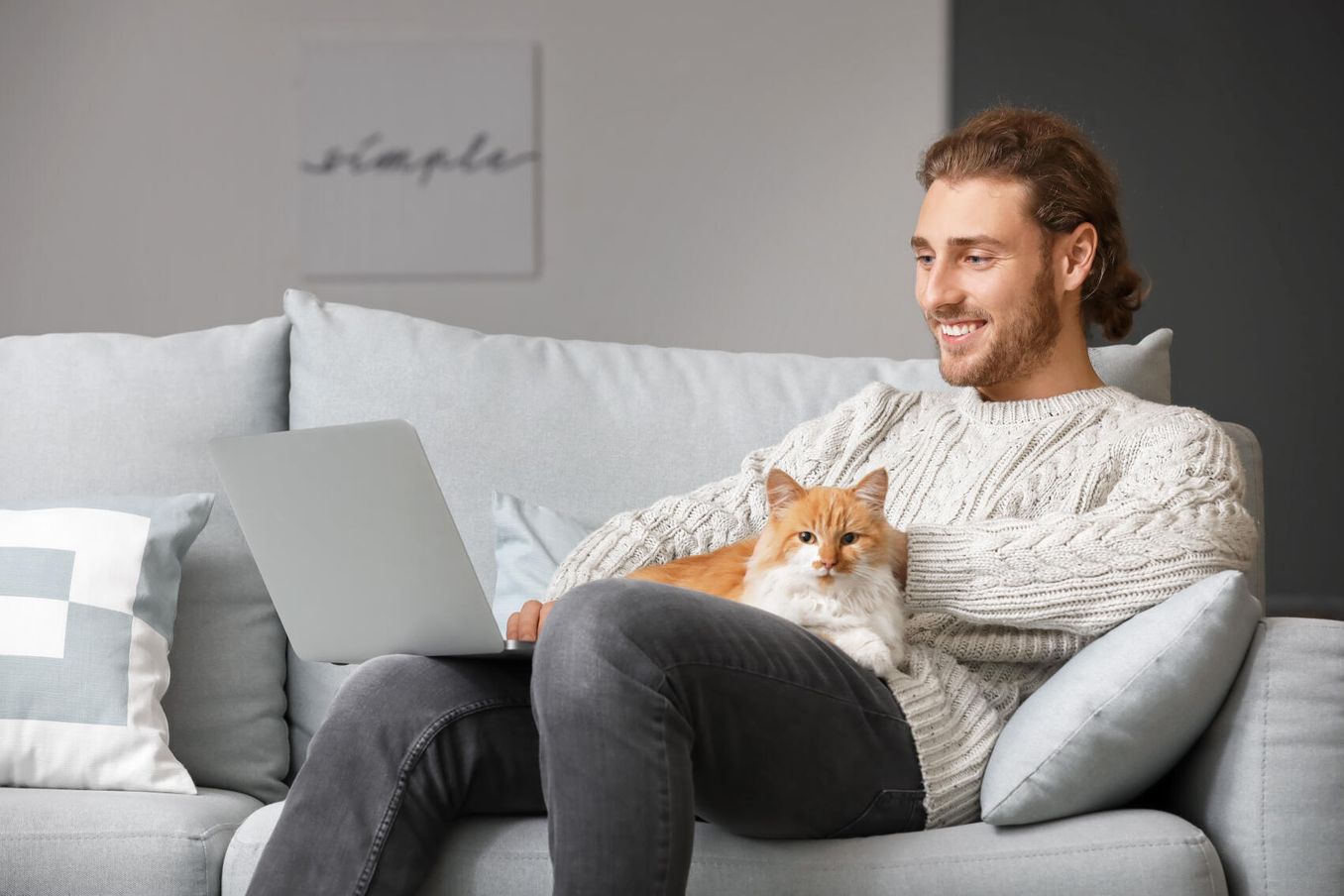 Online Studieren – Mann sitzt mit Katze und Laptop auf dem Sofa