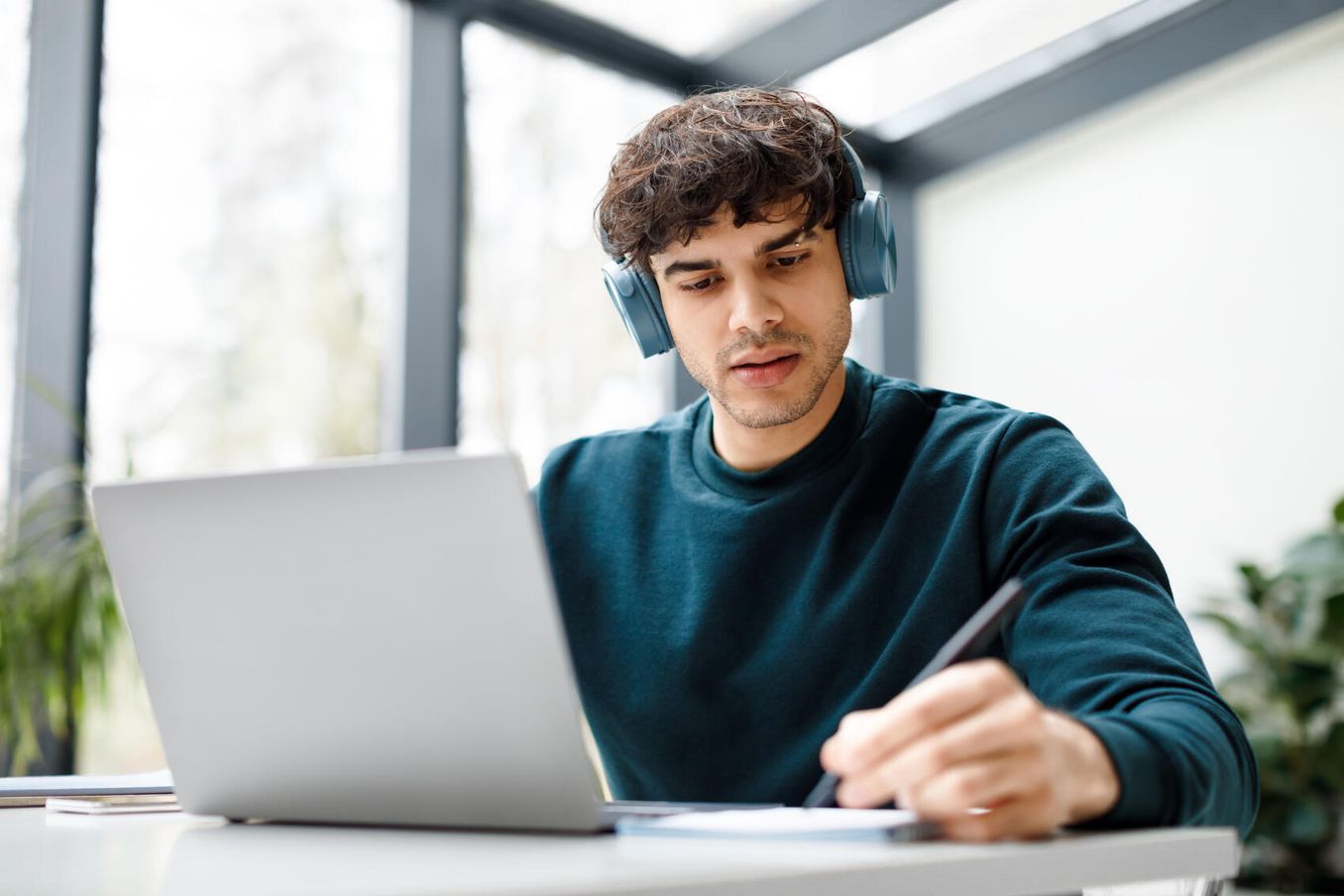 Student mit Kopfhörern schreibt Seminararbeit am Laptop