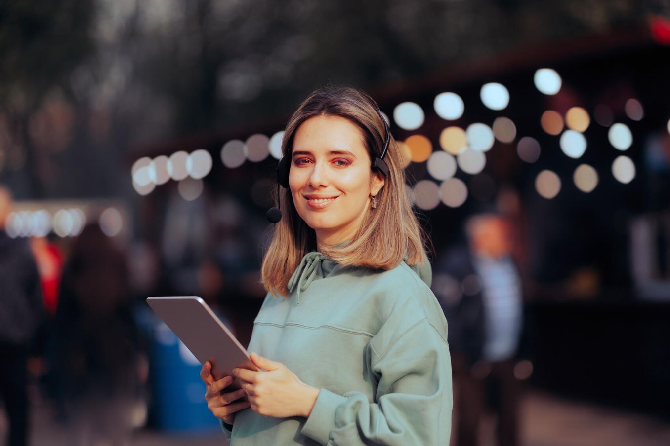 Eventmanagement Studium – Frau mit Tablet und Headset laechelt