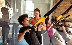 Studium Sportwissenschaft – Fitnesstrainerin unterstützt bei Übung Studium Sportwissenschaft – Fitnesstrainerin unterstuetzt bei Uebung