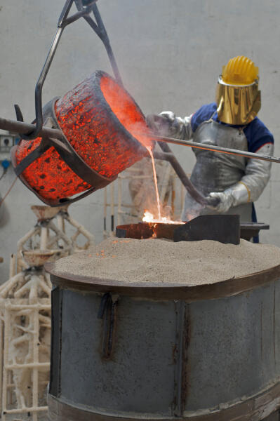 Gießereimechaniker gießt Metall in Gussformen Gießereimechaniker gießt Metall in Gussformen