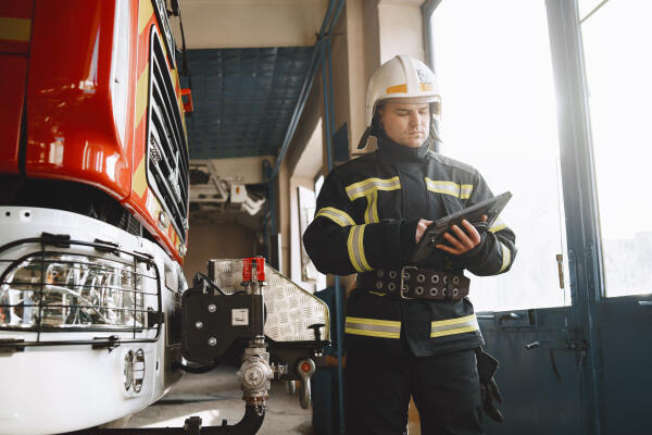 Beamter bei der Feuerwehr überprüft Fahrzeuge Beamter bei der Feuerwehr überprüft Fahrzeuge