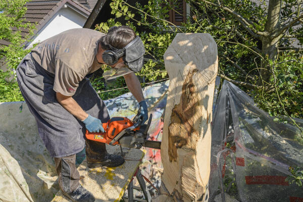 Holzbildhauer arbeitet mit Motorsäge Holzbildhauer arbeitet mit Motorsäge