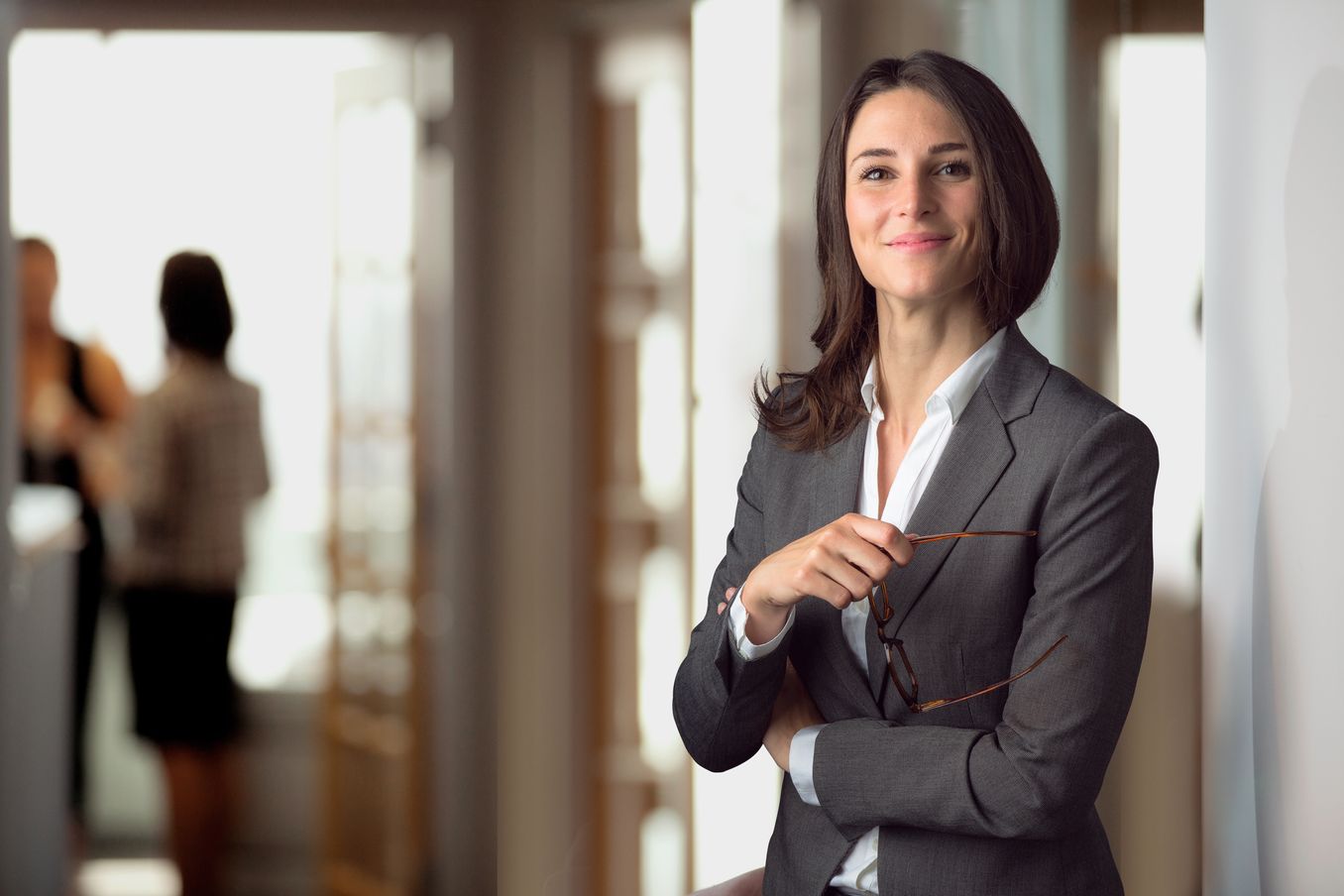 Management Studium – Managerin haelt ihre Brille in der Hand und laechelt