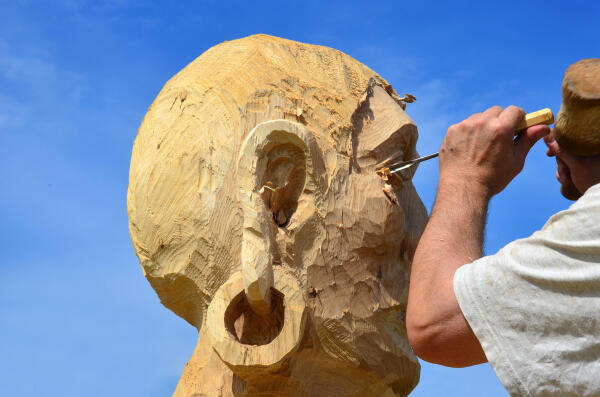 Holzbildhauer arbeitet Gesichtsform heraus Holzbildhauer arbeitet Gesichtsform heraus