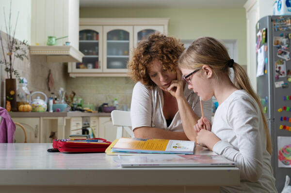 Kinderdorfmutter hilft einem Kind bei den Hausaufgaben Kinderdorfmutter hilft einem Kind bei den Hausaufgaben