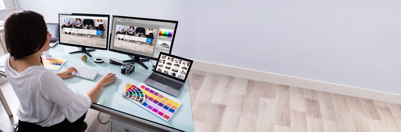 Mediendesign Studium – Mediendesignerin arbeitet vor drei Bildschirmen am Schreibtisch