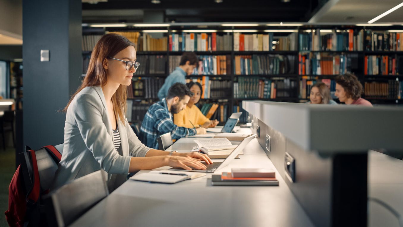 Magister Studium - Studentin arbeitet in der Bibliothek an ihrer Magisterarbeit