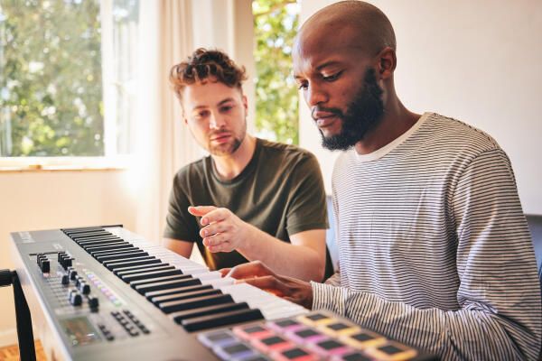 Klavierlehrer uebt mit Schueler auf Keyboard