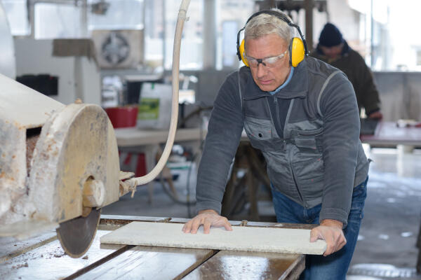 Naturwerksteinmechaniker schneidet Steinplatte