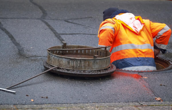 Fachkraft steigt Abwasserkanal hinab Fachkraft steigt Abwasserkanal hinab