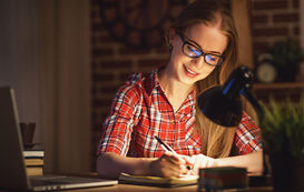 Studentin beim Seminararbeit schreiben an ihrem Schreibtisch Studentin beim Seminararbeit schreiben an ihrem Schreibtisch