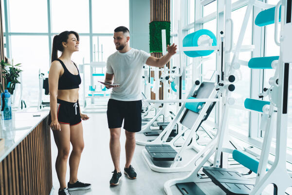 Fitnesstrainer zeigt verschiedene Geräte Fitnesstrainer zeigt verschiedene Geräte