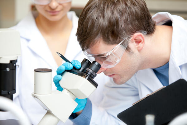 Chemielaborjungwerker verwendet Mikroskop Chemielaborjungwerker verwendet Mikroskop