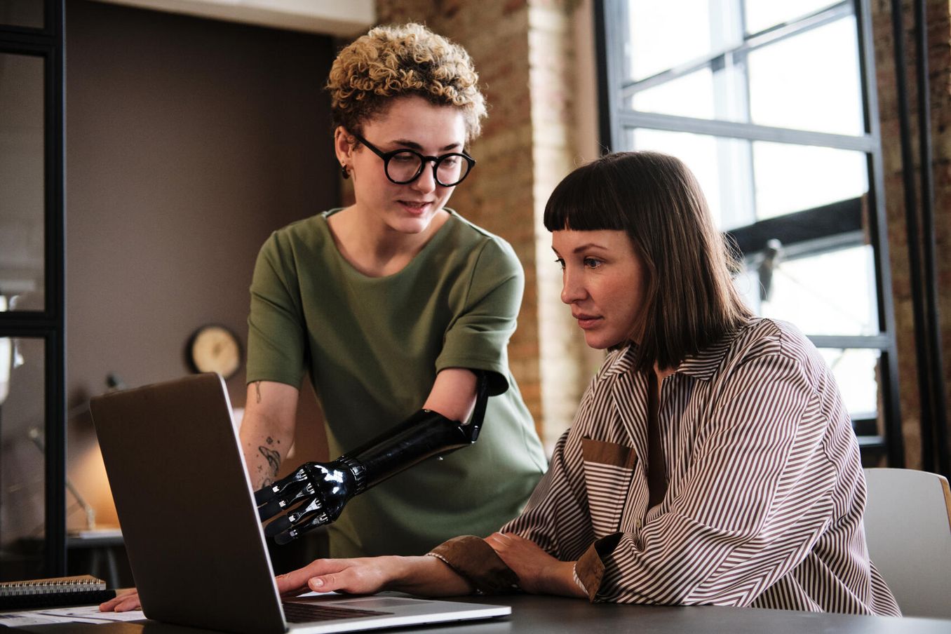 Studieren mit Behinderung – Studentin mit Armprothese spricht mit Kommilitonin