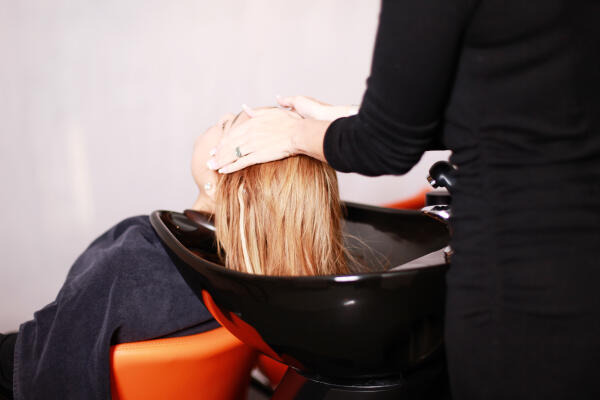 Friseurin wäscht Haare einer Kundin