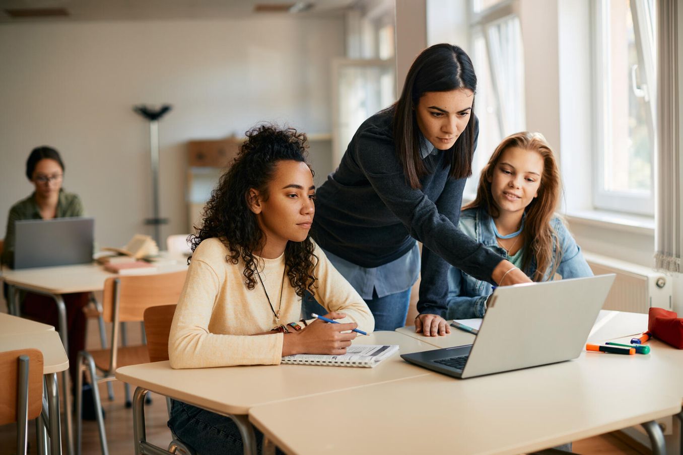 Studiengänge mit Pädagogik – Lehrerin erklärt Schülerinnen eine Aufgabe