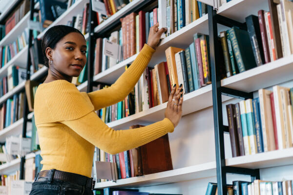 Buchhändlerin sucht für Kunden passende Bücher heraus Buchhändlerin sucht für Kunden passende Bücher heraus