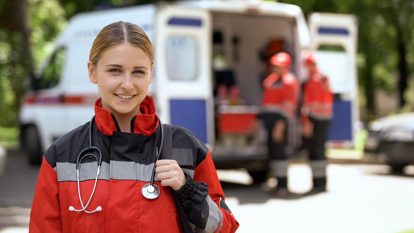 Rettungswesen Studium – Studierende steht vor einem Krankenwagen in Uniform