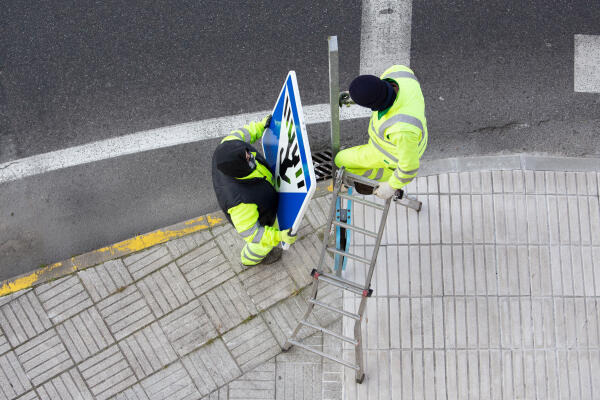 Straßenwärter bringen Straßenschild an Straßenwärter bringen Straßenschild an