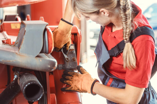 Land- und Baumaschinenmechatronikerin führt Reparaturen durch Land- und Baumaschinenmechatronikerin führt Reparaturen durch