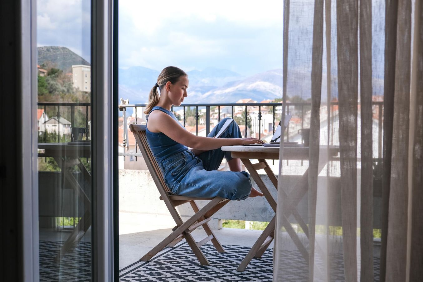 Work-Life-Balance – Auszubildende auf Workation arbeitet am Laptop mit Ausblick
