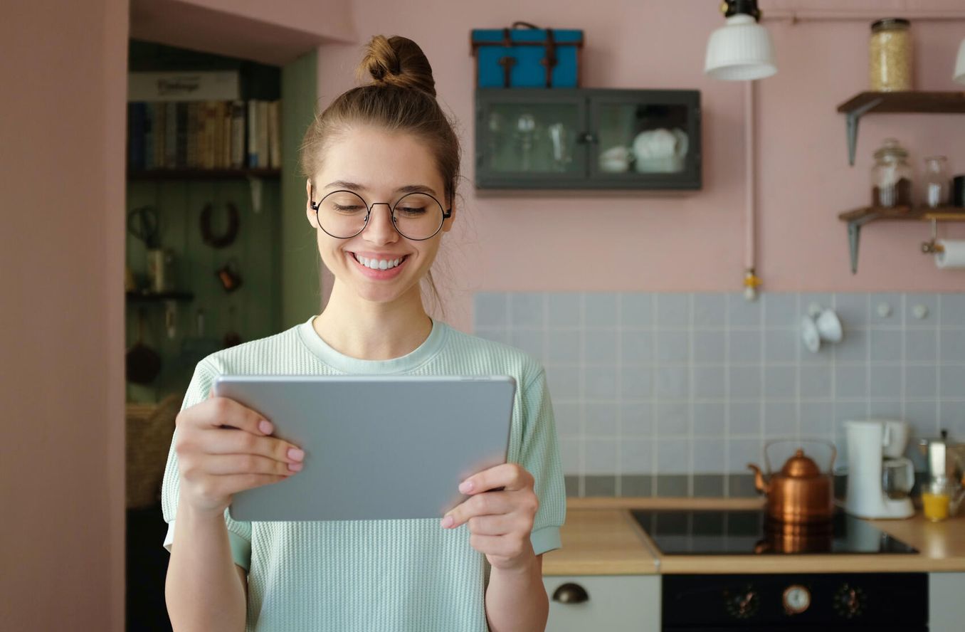 Junge Frau schreibt Studentenwohnung Bewerbung am Tablet