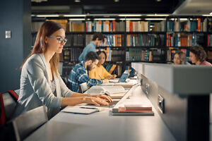 Studentin in der Bibliothek beim wissenschaftlichen Schreiben Studentin in der Bibliothek beim wissenschaftlichen Schreiben
