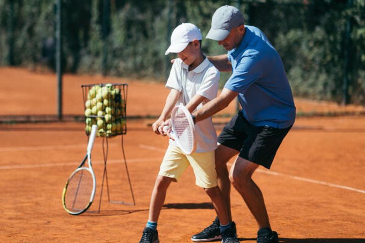 Tennislehrer mit Schüler