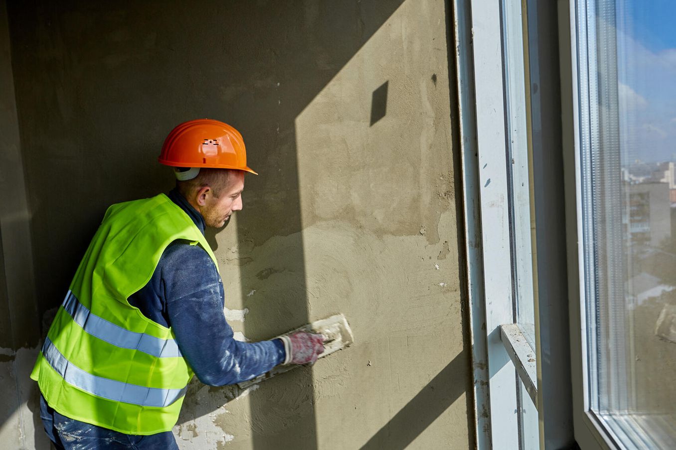 Fachkraft Holz- und Bautenschutzarbeiten verputzt Wand