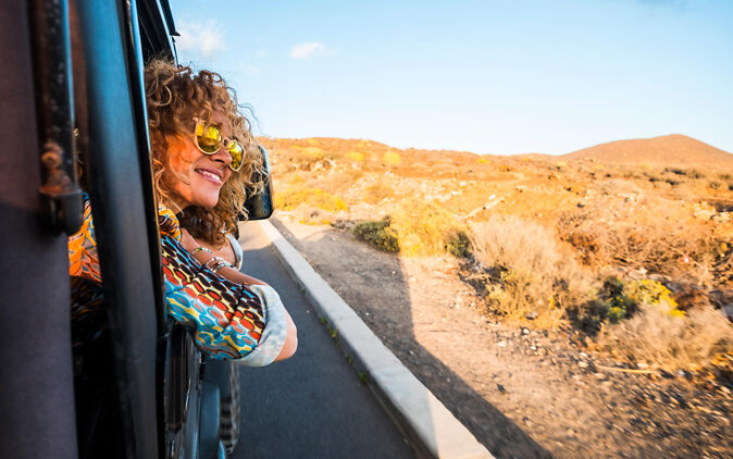 Auslandsaufenthalt – Studentin lehnt sich aus dem Autofenster im Ausland Auslandsaufenthalt – Studentin lehnt sich aus dem Autofenster im Ausland