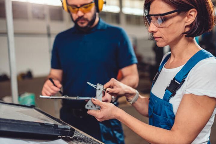 Schweißerin prüft fertiges Bauteil
