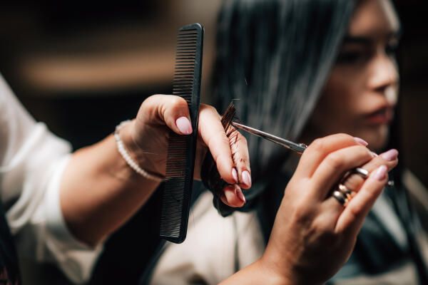 Friseurin schneidet Haare einer Kundin