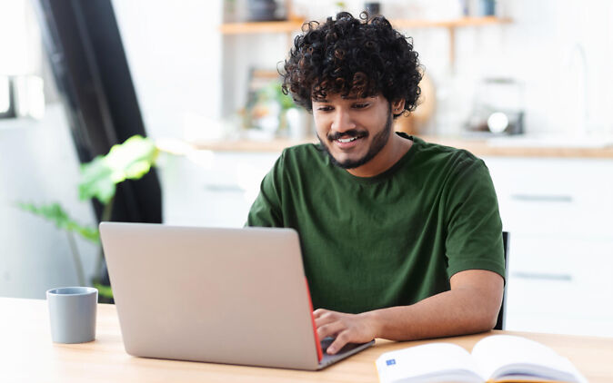 Junger Mann checkt online seine Studienmöglichkeiten Junger Mann checkt online seine Studienmoeglichkeiten