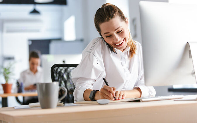 Kaufmann Weiterbildung – Junge Frau sitzt an Schreibtisch und telefoniert" Kaufmann Weiterbildung – Junge Frau sitzt an Schreibtisch und telefoniert"