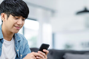 Kindergeld Student – Junger Mann sitzt in seiner Wohnung Kindergeld Student – Junger Mann sitzt in seiner Wohnung