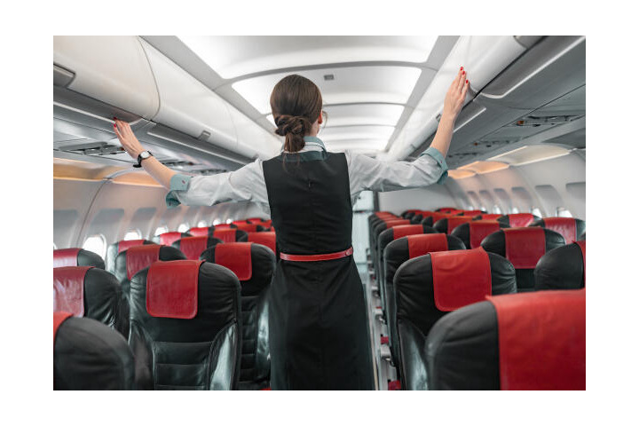 Flugbegleiterin überprüft Gepäckfächer