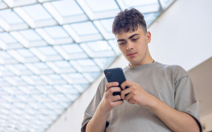 Junger Mann richtet WhatsApp-Stellenalarm auf seinem Smartphone ein Junger Mann richtet WhatsApp-Stellenalarm auf seinem Smartphone ein