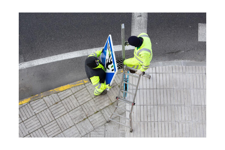 Straßenwärter bringen Straßenschild an.jpeg