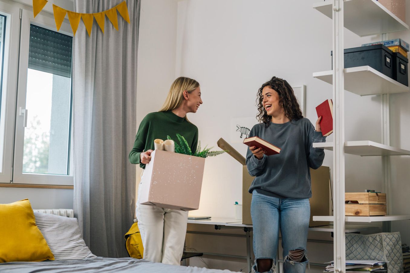 Studierende hilft ihrer Mitbewohnerin im Studentenwohnheim beim Auspacken