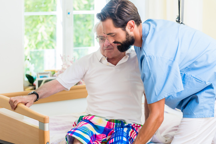 Pflegehelfer assistiert Patient beim Aufstehen